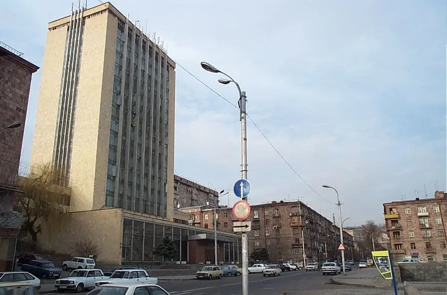 La rue Saryan à Erevan vers 2001 : à gauche, la haute tour claire de Haypost et son socle vitré bas ; le long de la rue, d’anciens immeubles d’habitation en tuf et des voitures de l’époque